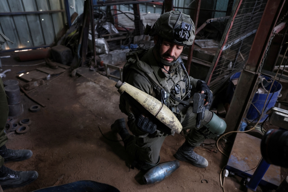An Israeli soldiers holds a piece of metal inside, what the Israeli army said is a steel factory where rockets and other ammunition was produced, as he operates, amid the ongoing conflict between Israel and the Palestinian Islamist group Hamas, in Gaza, January 8, 2024. — Reuters