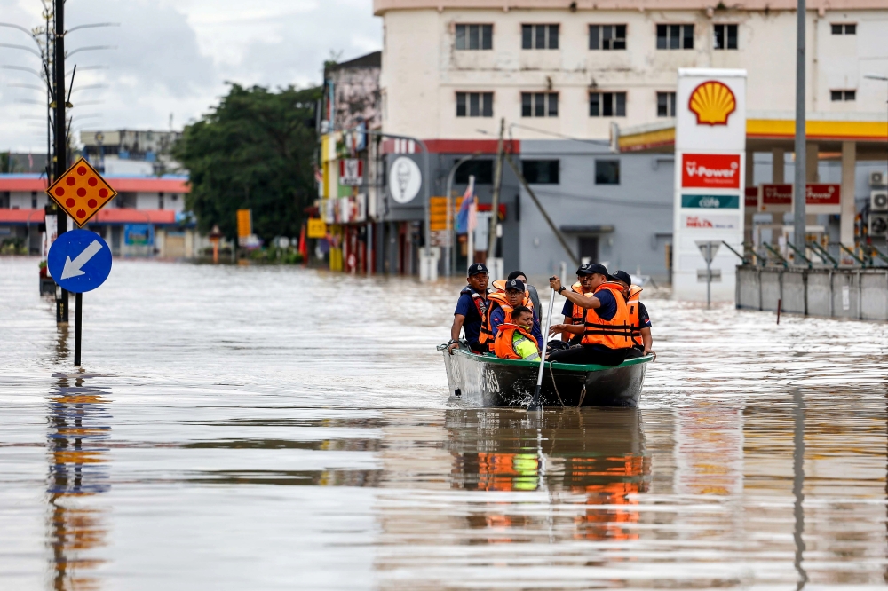 Police officers use a rescue boat to bring victims trapped by the floods in Kota Tinggi city centre, January 9, 2024. — Bernama pic 