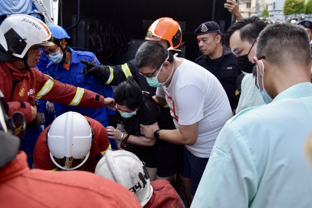 The deceased’s distraught family members inspect the body after it was retrieved from the building. — Borneo Post pic 