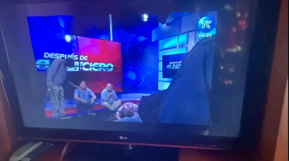 Workers lie on the floor as hooded and armed people take over a tv studio of Ecuador's TV station TC during a live broadcast, in this still image of a Reuters' recording of the affair of TC signal channel, in Guayaquil, Ecuador, January 9, 2024. — Screen capture via Reuters Tv/via Reuters