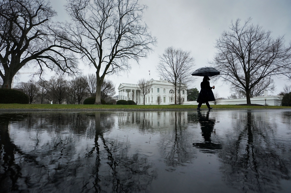 A reporter, arriving for work, walks up the driveway toward the White House on a rain-soaked morning in Washington January 9, 2024. — Reuters pic