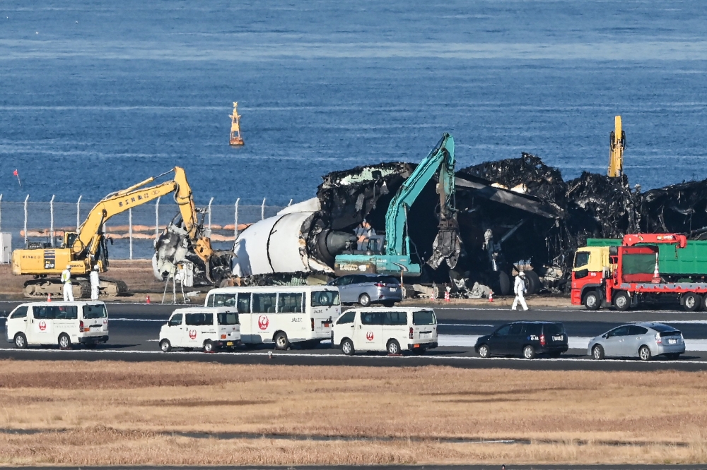 Officials use heavy equipment to remove the remaining debris of a Japan Airlines (JAL) passenger plane from the runway area at Tokyo International Airport at Haneda on January 5, 2024, three days after the JAL airliner hit a smaller coast guard plane on the ground. Five of the six people on the smaller aircraft died but all 379 people onboard the Japan Airlines Airbus were evacuated just before it was engulfed in flames. — AFP pic