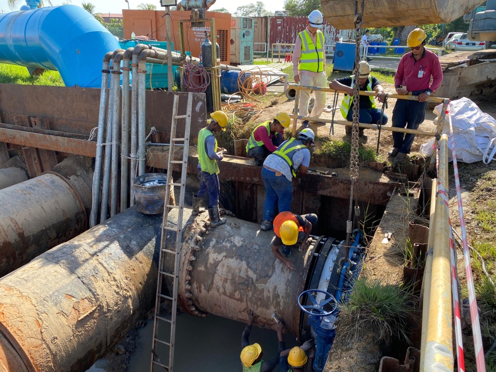 Workers replacing one of two aged and leaking valves at the Sungai Dua Water Treatment Plant on January 10, 2024. — Picture by Opalyn Mok