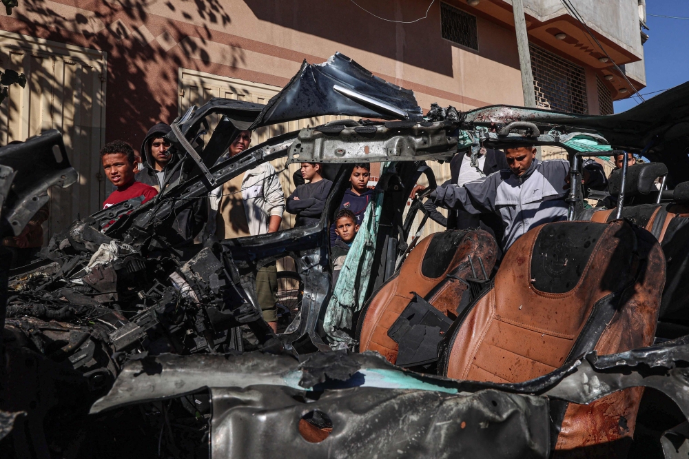 People check the car in which two journalists,Mustafa Thuria, a video stringer for AFP news agency, and Hamza Wael Dahdouh, a journalist with Al Jazeera television network, were killed in a reported Israeli strike in Rafah in the Gaza Strip on January 7, 2024. — AFP pic