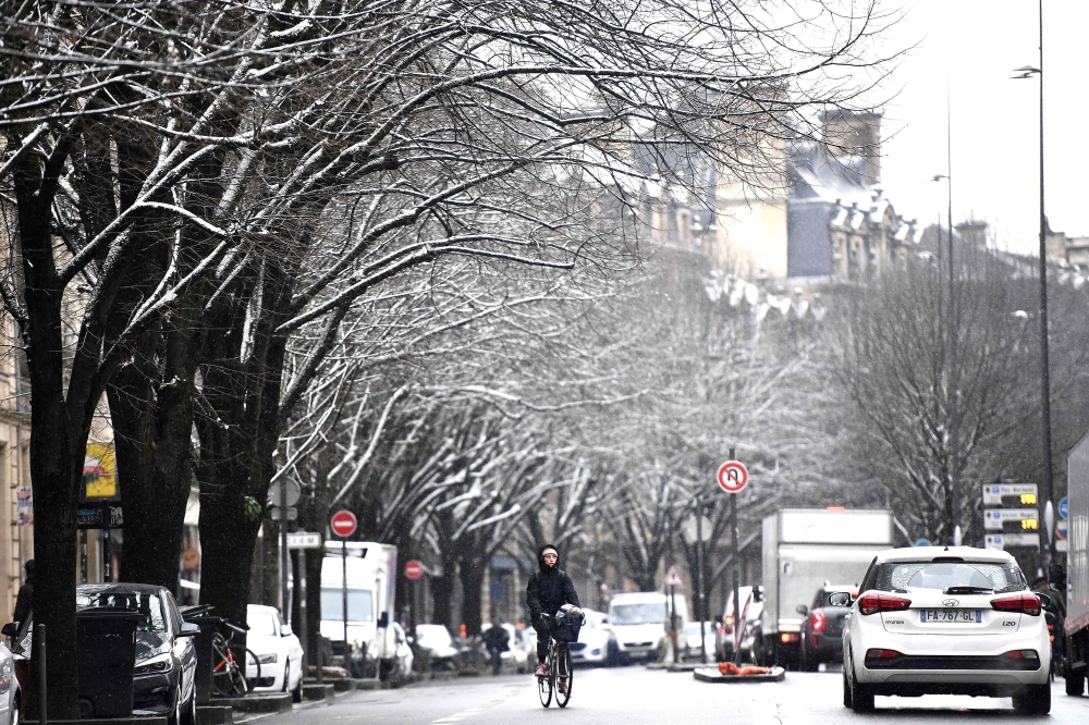 A woman bikes down a street during a snowfall in Bordeaux, south-western France, on January 10, 2024. ― AFP pic