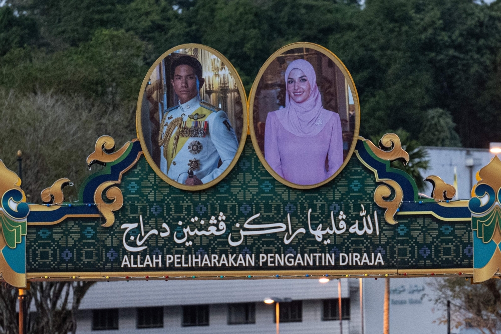 The portraits of groom Prince Abdul Mateen and bride Anisha Rosnah are pictured on a billboard over a road ahead of their wedding in Brunei on Borneo island on January 10, 2024. — AFP pic