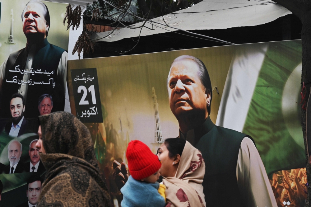 People walk past a banner of the Pakistan Muslim League Nawaz (PML N) party with an image of former prime minister of Pakistan and candidate Nawaz Sharif in Lahore on January 9, 2024, ahead of Pakistan's upcoming general election. — AFP pic 