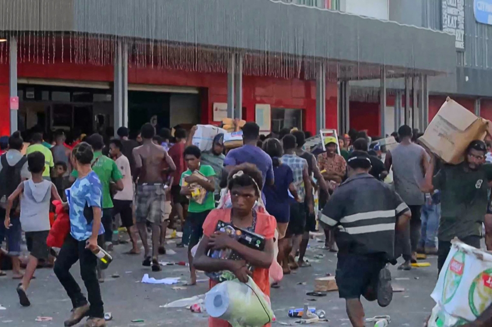This screen grab from AFPTV video footage taken on January 10, 2024 shows people carrying items as crowds leave shops with looted goods amid a state of unrest in Port Moresby. — AFP pic 