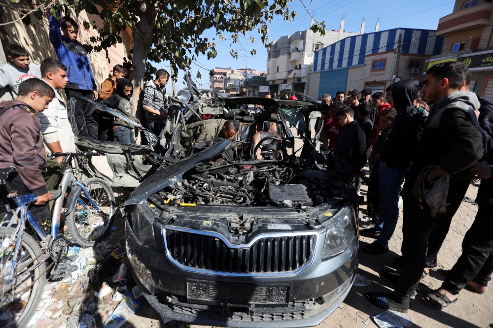 Palestinians inspect the remains of a car where Palestinian journalist Hamza Al-Dahdouh was killed along with another journalist in an Israeli strike, in Rafah in the southern Gaza Strip, January 7, 2024. — Reuters pic