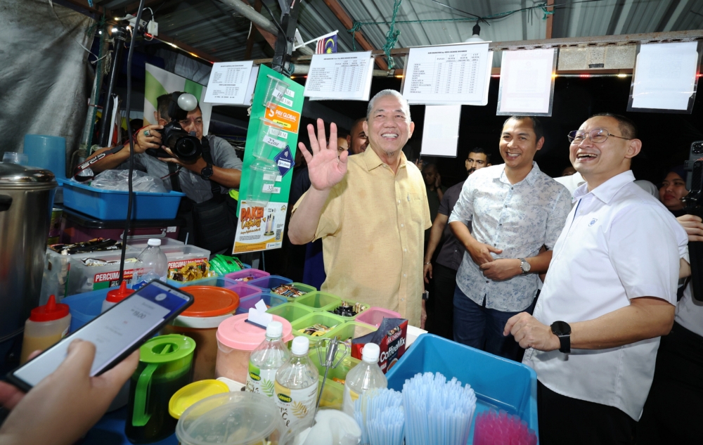 Deputy Prime Minister Datuk Seri Fadillah Yusof waves to traders after using e-money at the opening of cashless night market and e-money at Metrocity night market in Kuching, January 12, 2024. — Bernama pic 