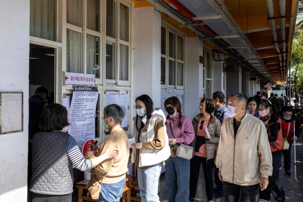 People wait in line to cast their ballots and vote in the presidential election at a polling station at an elementary school in New Taipei City January 13, 2024. — AFP pic