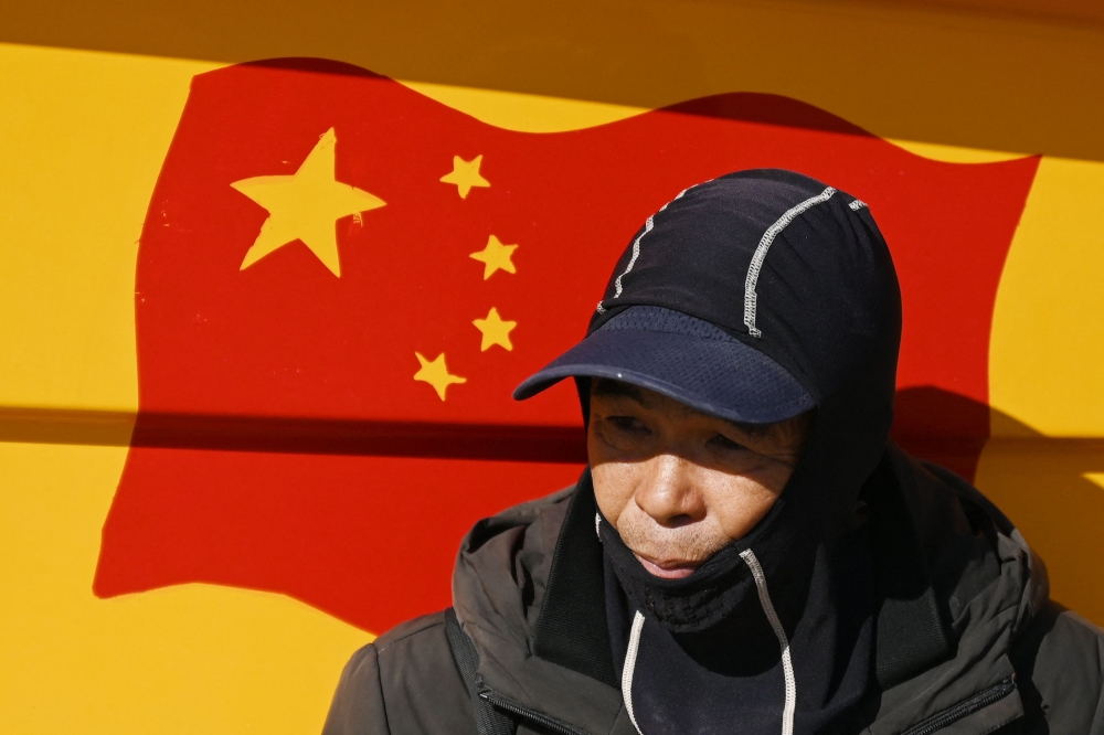 A man rests beside a Chinese flag painted on a boat on a beach on Pingtan Island, the closest point in China to Taiwan’s main island, in China’s southeast Fujian province, on January 13, 2024, the day of Taiwan’s Presidential election. — AFP pic