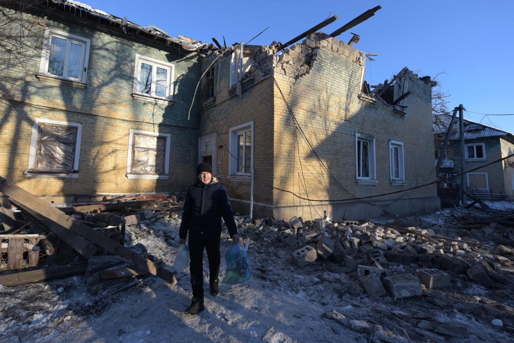 A man carries belongings out of a damaged two-storey housing block hit by recent shelling in Makiivka (Makeyevka), Russian-controlled Ukraine, amid the Russia-Ukraine conflict on January 12, 2024. — AFP pic