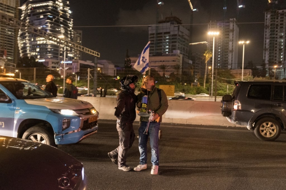 A protester is restrained by an Israeli policeman while blocking a highway during a demonstration in Tel Aviv, on January 13, 2024, after almost 100 days of war between Israel and the militant Hamas group in Gaza. — AFP pic