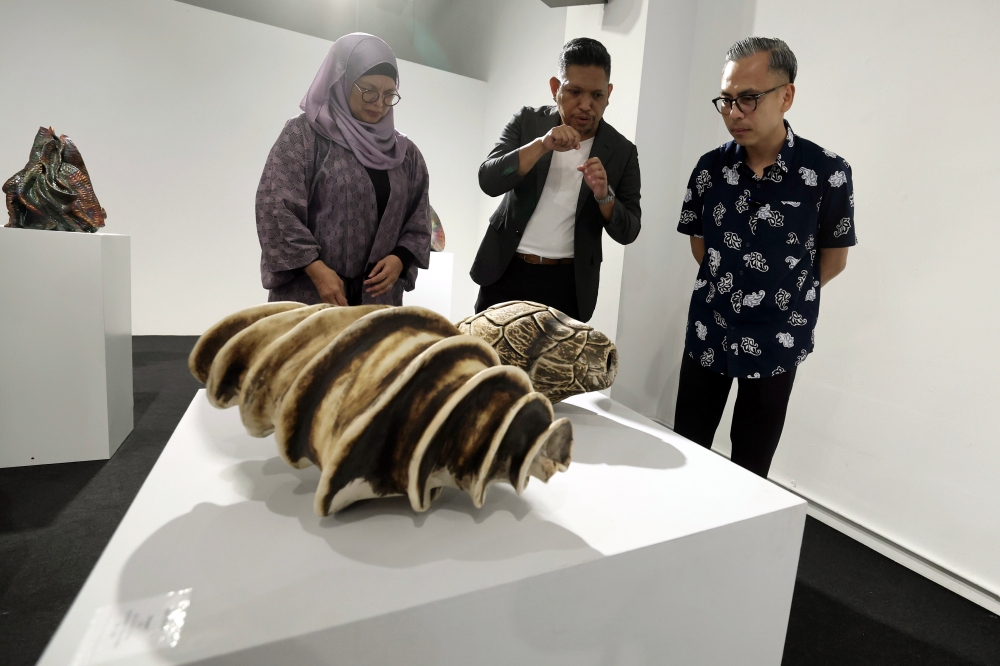 Communications Minister Fahmi Fadzil (right) listens as ceramic artist Adil Abdul Ghani (centre) explains his artwork during the ‘Life: Magnified — The Main Show’ exhibition at Zhan Art in Kuala Lumpur January 13, 2024. — Bernama pic