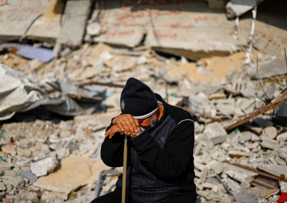 Ziad Mansour, a neighbour of the Abu Aweidah family, sits next to writing painted on a wall amid the rubble of the family's house, which was destroyed in a deadly Israeli strike amid the ongoing conflict between Israel and the Palestinian Islamist group Hamas, in Rafah, Gaza Strip, January 9, 2024. — Reuters pic