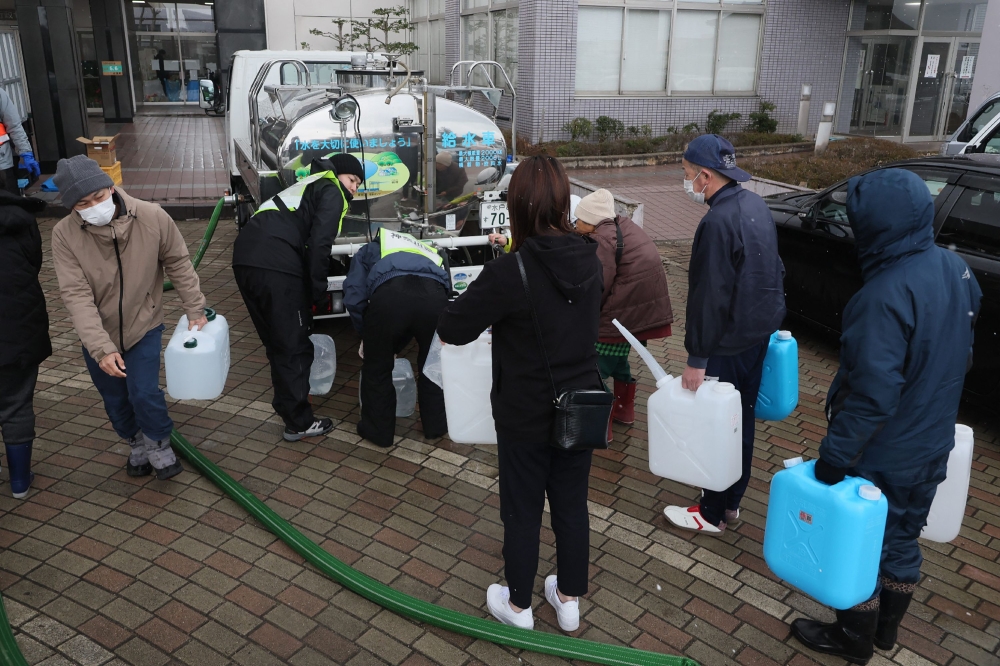 This photo taken on January 15, 2024 shows local residents receiving water supply assistance in Shika town, Ishikawa prefecture, two weeks after a major 7.5 magnitude earthquake struck the Noto region in Ishikawa prefecture on New Year's Day. ― AFP pic