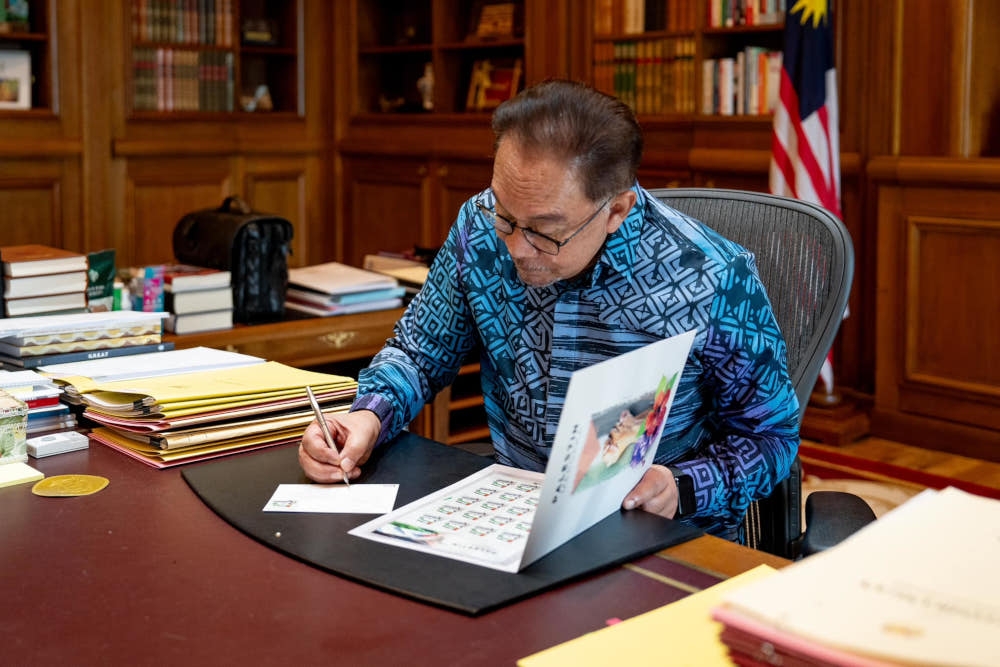 Prime Minister Datuk Seri Anwar Ibrahim signs the special postcard addressed to UN Secretary-General Antonio Guterres, January 17, 2024. — Picture from Facebook/Anwar Ibrahim 