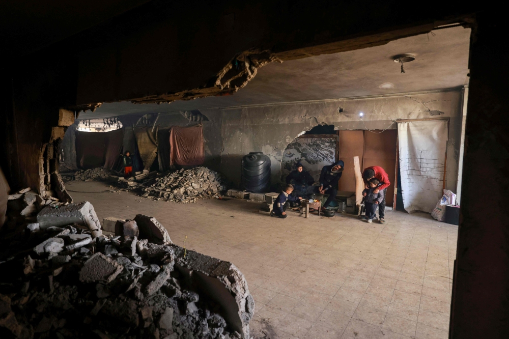 Displaced Palestinians prepare food as they take shelter inside a building damaged during Israeli bombardment in Rafah in the southern Gaza Strip on January 17, 2024, amid ongoing battles between Israel and the Palestinian militant group Hamas. — AFP pic