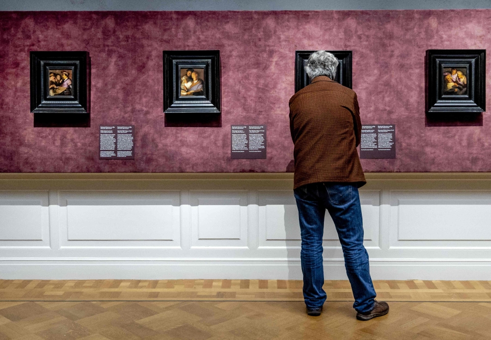 A person looks at painting during the preview of the exhibition ‘Rembrandt’s four senses — his first paintings’ in the De Lakenhal museum in Leiden January 18, 2024. The museum is celebrating its 150th anniversary and is presenting four paintings by Rembrandt that he made when he lived in Leiden as an 18-year-old. — Remko de Waal/ANP/AFP pic 
