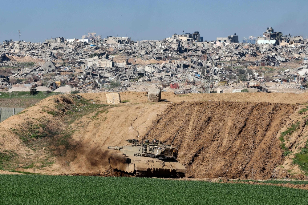 A picture taken from a position in southern Israel along the border with the Gaza Strip on January 18, 2024, shows an Israeli tank positioned behind a sand wall and damaged buildings in Gaza amid continuing battles between Israel and the militant group Hamas. — AFP pic