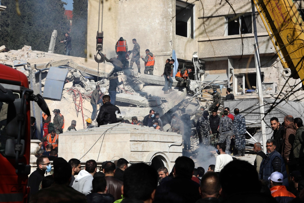 Security and emergency personnel search the rubble of a building destroyed in a reported Israeli strike in Damascus on January 20, 2024. — AFP pic
