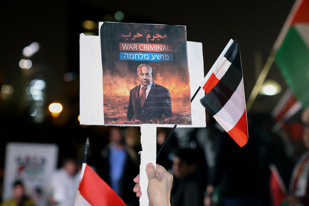 A Kuwaiti man holds a placard bearing the portrait of Israeli Prime Minister Benjamin Netanyahu during a rally in solidarity with the people of Gaza at Iradah Square in Kuwait City on January 14, 2024, as the ongoing war between Israel and the Palestinian militant group Hamas enters its 100th day. — AFP pic