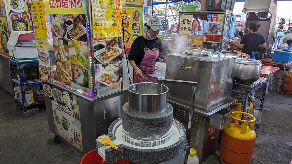 The stone mill with which the 'rice milk' is freshly made. Not something you see every day by a stall.