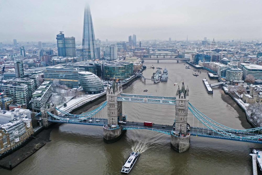 An aerial view shows snow-covered offices and buildings including the Shard skyscraper, as a boat passes under Tower Bridge on the River Thames, from Wapping, east London on December 12, 2022. Australian-born private equity entrepreneur Angus Murray has submitted the proposal to transform the history-rich yet little-known Kingsway Exchange Tunnels into a major tourist attraction. — AFP pic 