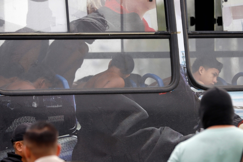 Arrested men who attempted to take over a hospital sit in a police bus in Guayas, Ecuador, on January 21, 2023. — AFP pic