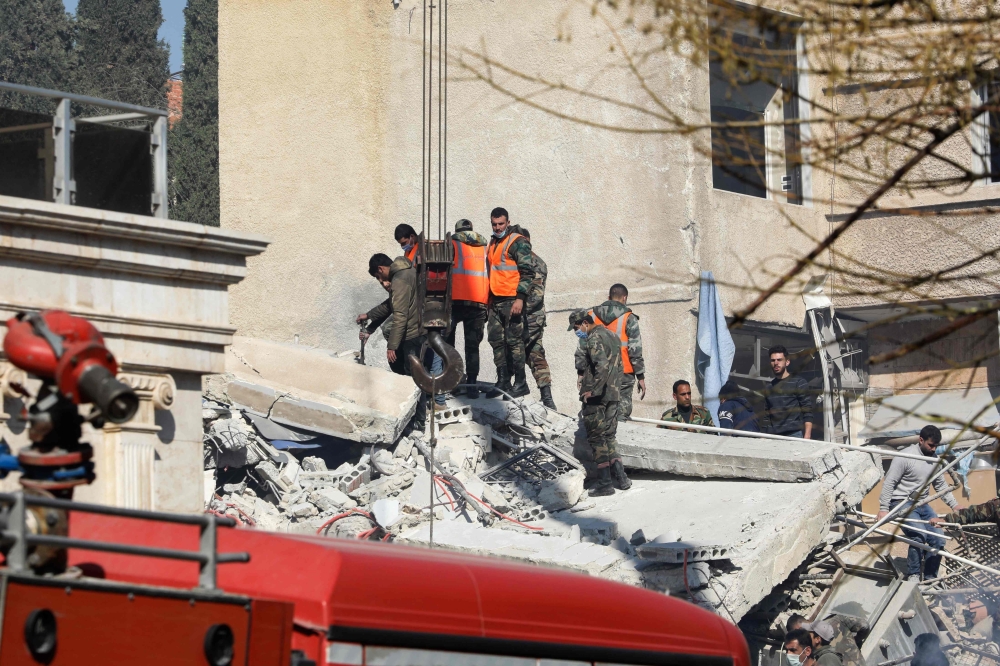 Security and emergency personnel search the rubble of a building destroyed in a reported Israeli strike in Damascus on January 20, 2024. — AFP pic