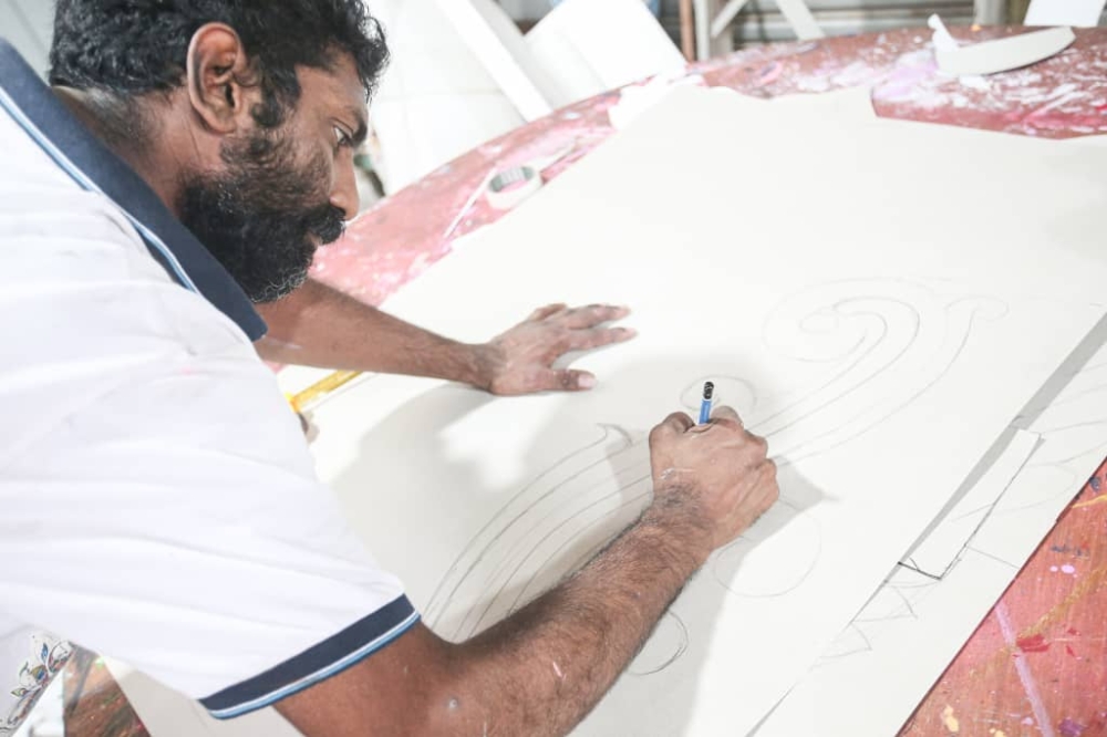 According to Lawrance, preparation for a 'kavadi' starts with sketching on a cardboard. — Picture by Farhan Najib