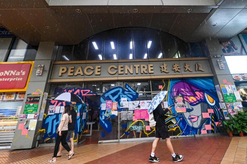 In this photograph taken on January 19, 2024, people walk past the entrance of the Peace Centre, an abandoned mall turned into an unexpected art enclave, in Singapore. — AFP pic