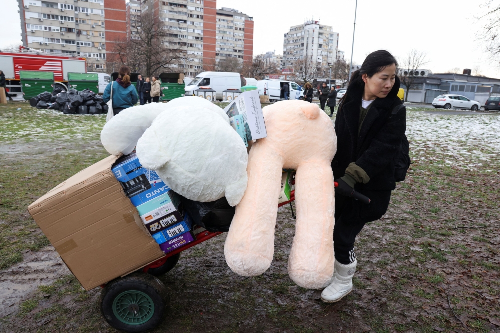 People evacuate stuff from stores as a fire breaks out at the Chinese shopping centre, in Belgrade, Serbia, January 24, 2024. — Reuters pic