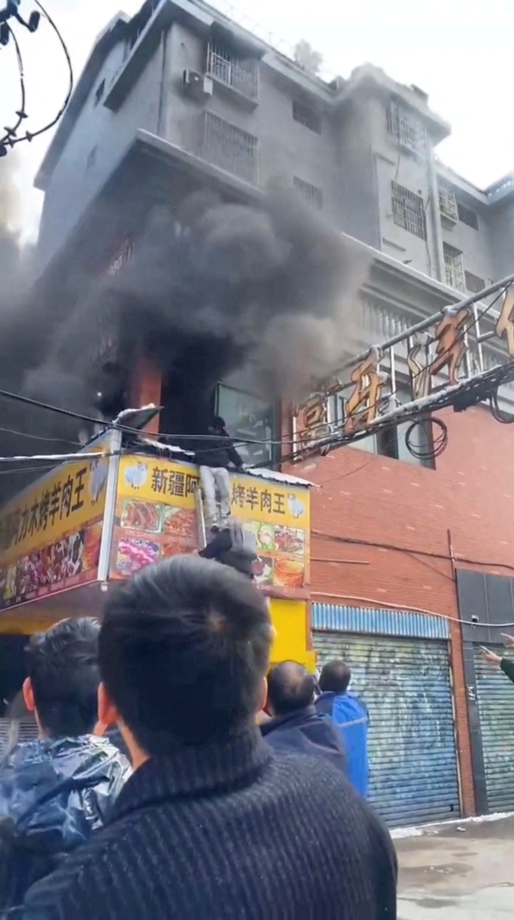 A person climbs out of a building after a street shop caught fire in Xinyu City of Jiangxi Province, China in this screengrab obtained from a social media video. — Reuters pic