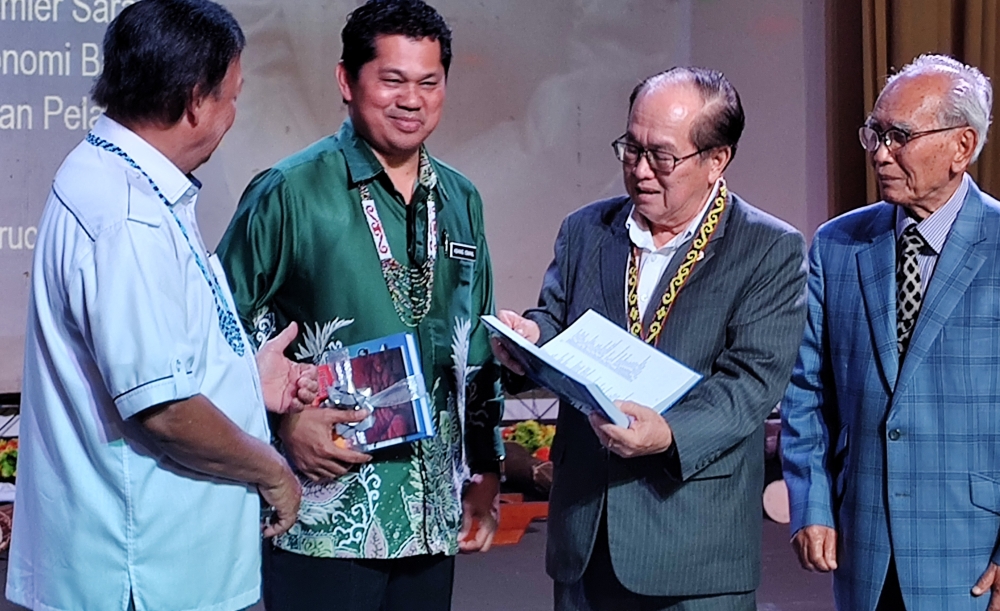 Deputy Premier Datuk Amar Douglas Uggah (second, right) browses through a copy of the English-Iban Dictionary after its launch on January 25, 2024. — Picture by  Sulok Tawie
