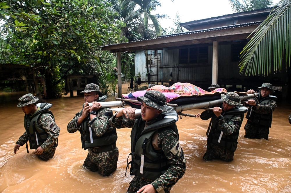 Members of the Armed Forces had to wade through floods to carry the remains of an elderly man, Kelthom Mat, 84, who died at 9am due to old age at his residence in Kampung Bukit Tadok, Kuala Terengganu, January 25, 2024. — Bernama pic 