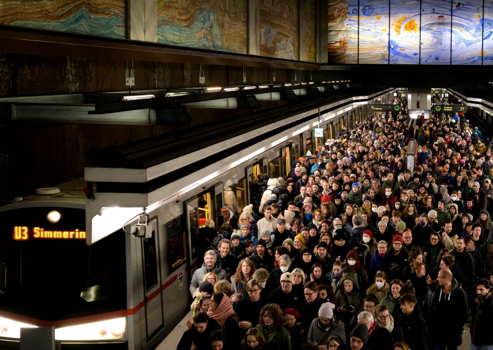 Crowds of people leave the U3 subway station Volstheather to attend a rally under the motto 'Defend Democracy' against right-wing extremism, racism and anti-Semitism as rain falls in front of the parliament in Vienna, Austria January 26, 2024. — AFP pic