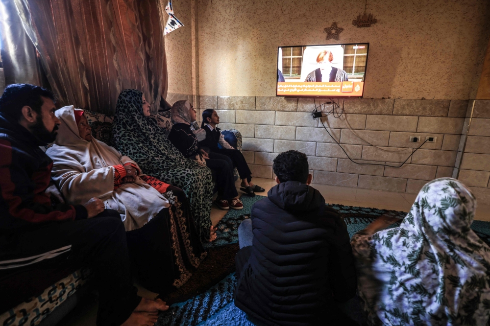 Members of a Palestinian family watch on a television set, the UN's top court in the Hague reading its initial decision in a case accusing Israel of genocide, in Rafah in the southern Gaza Strip on January 26, 2024. ¬— AFP pic