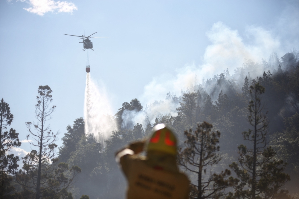 This handout picture released by Argentina’s National Parks shows a helicopter dropping water to put out a forest fire at Los Alerces National Park. — AFP pic/Argentina’s National Parks
