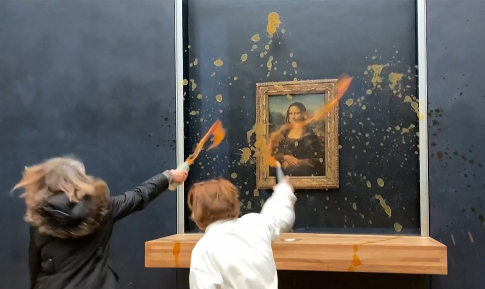 This image grab taken from AFPTV footage shows two environmental activists from the collective dubbed ‘Riposte Alimentaire’ (Food Retaliation) hurling soup at Leonardo Da Vinci's ‘Mona Lisa’ (La Joconde) painting, at the Louvre museum in Paris, on January 28, 2024. — AFP pic 