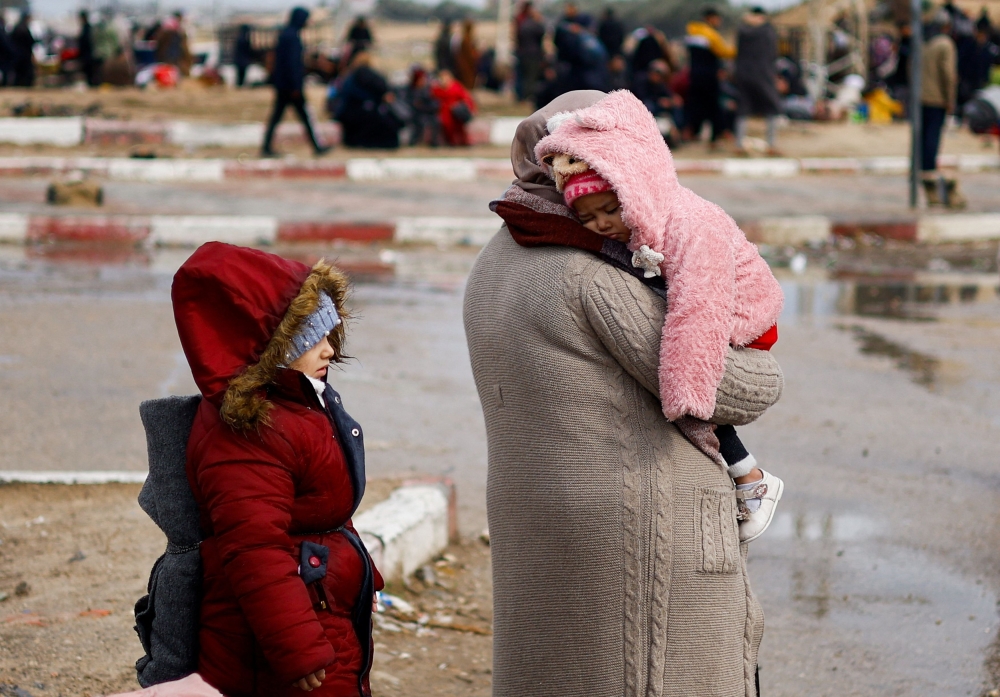A woman carries a child as Palestinians fleeing Khan Younis, due to the Israeli ground operation, move towards Rafah, amid the ongoing conflict between Israel and the Palestinian Islamist group Hamas, in the southern Gaza Strip, January 27, 2024. — Reuters pic