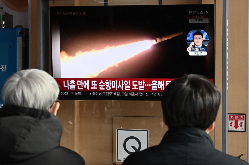 People watch a television screen showing a news broadcast with file footage of a North Korean missile test, at a railway station in Seoul on January 28, 2024. — AFP pic