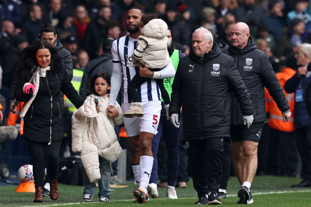 West Bromwich Albion's English defender #05 Kyle Bartley helps take members of his family away from an area of the ground where trouble has broken out between fans during the English FA Cup fourth round football match between West Bromwich Albion and Wolverhampton Wanderers at The Hawthorns stadium in West Bromwich. — AFP pic