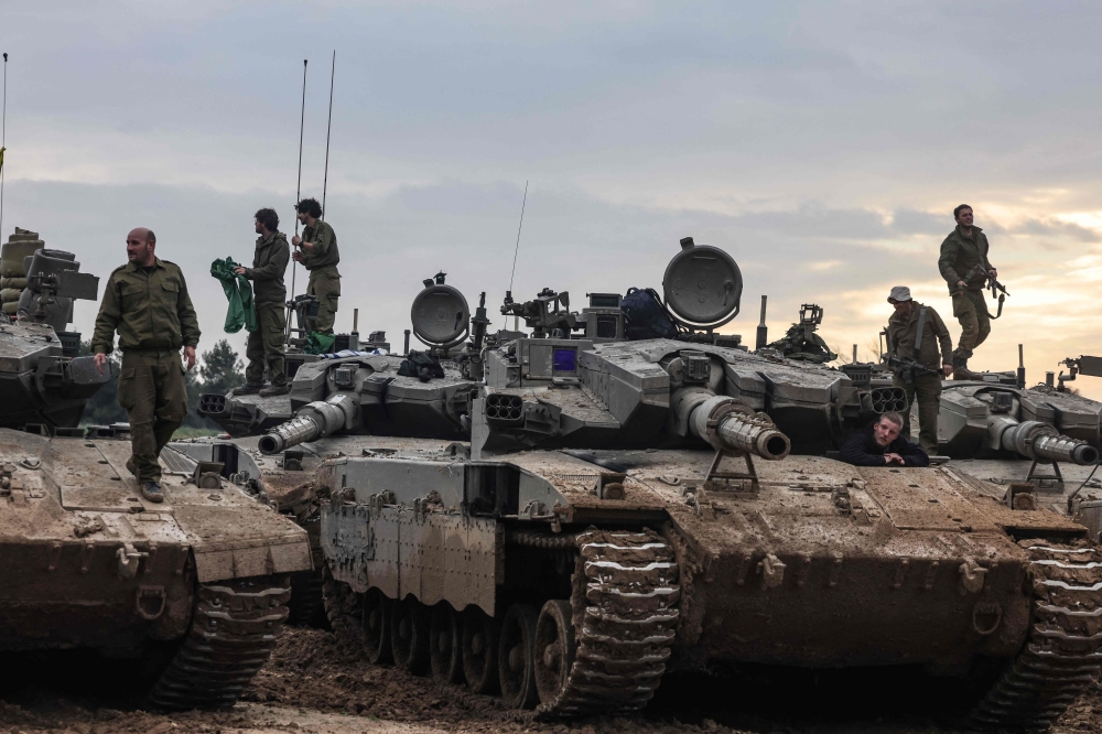 A picture taken from southern Israel along the border with the Gaza Strip shows Israeli soldiers ontop their tanks at a position upon their return from a mission in the Palestinian territory on January 28, 2024, amid ongoing battles between Israel and the Palestinian Hamas militant group. — AFP pic