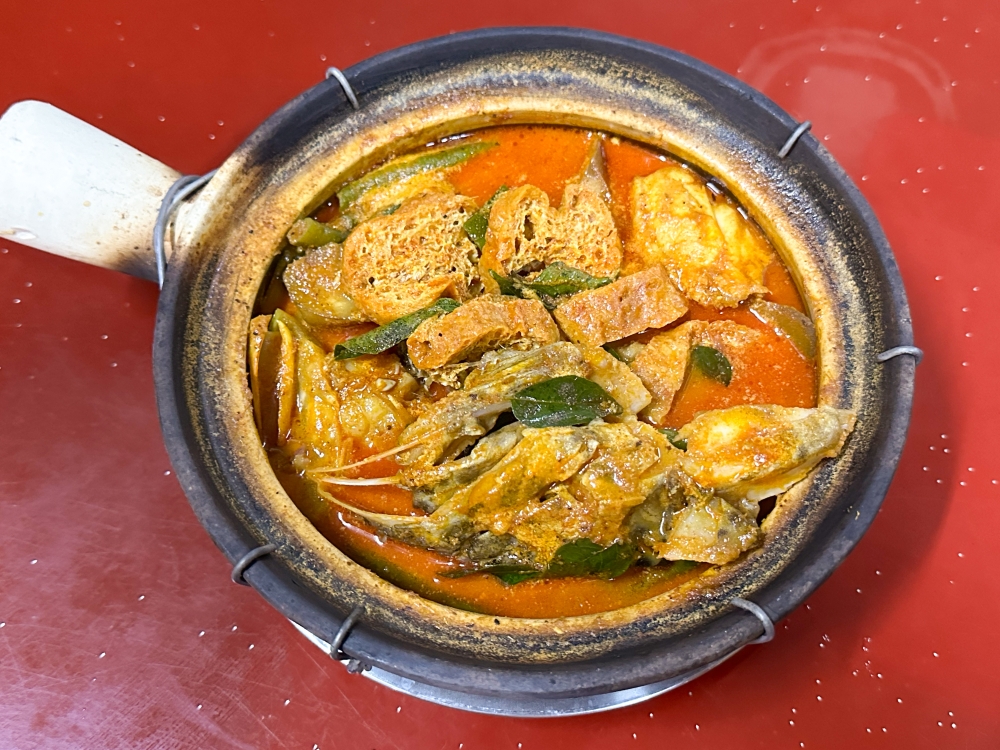 The orange hued curry is fragrant with lemongrass and chunky pieces of grouper fish head.