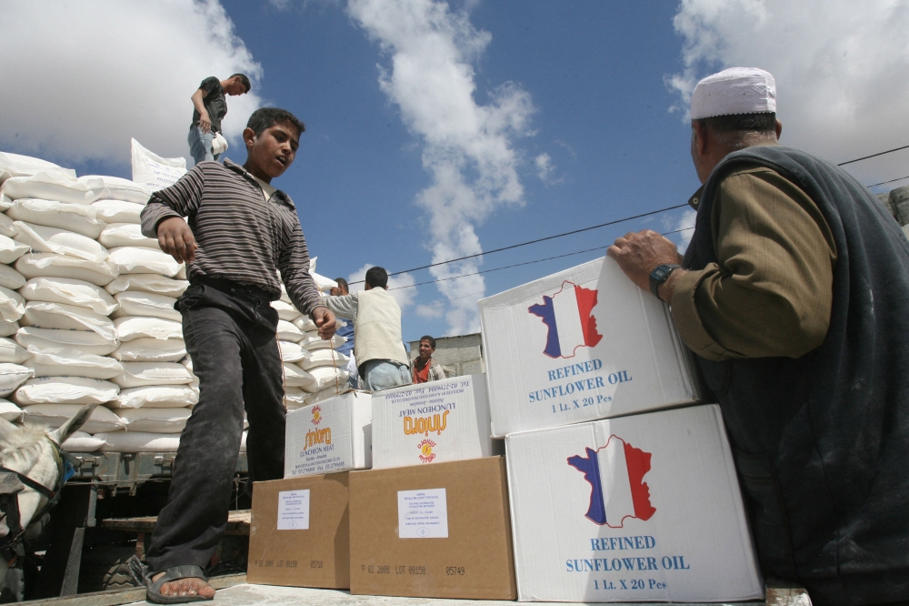 Palestinian refugees carry food aid they received from the United Nations Relief and Works Agency for Palestine Refugees (UNRWA) on April 24, 2008 in Rafah, southern Gaza Strip. — AFP pic