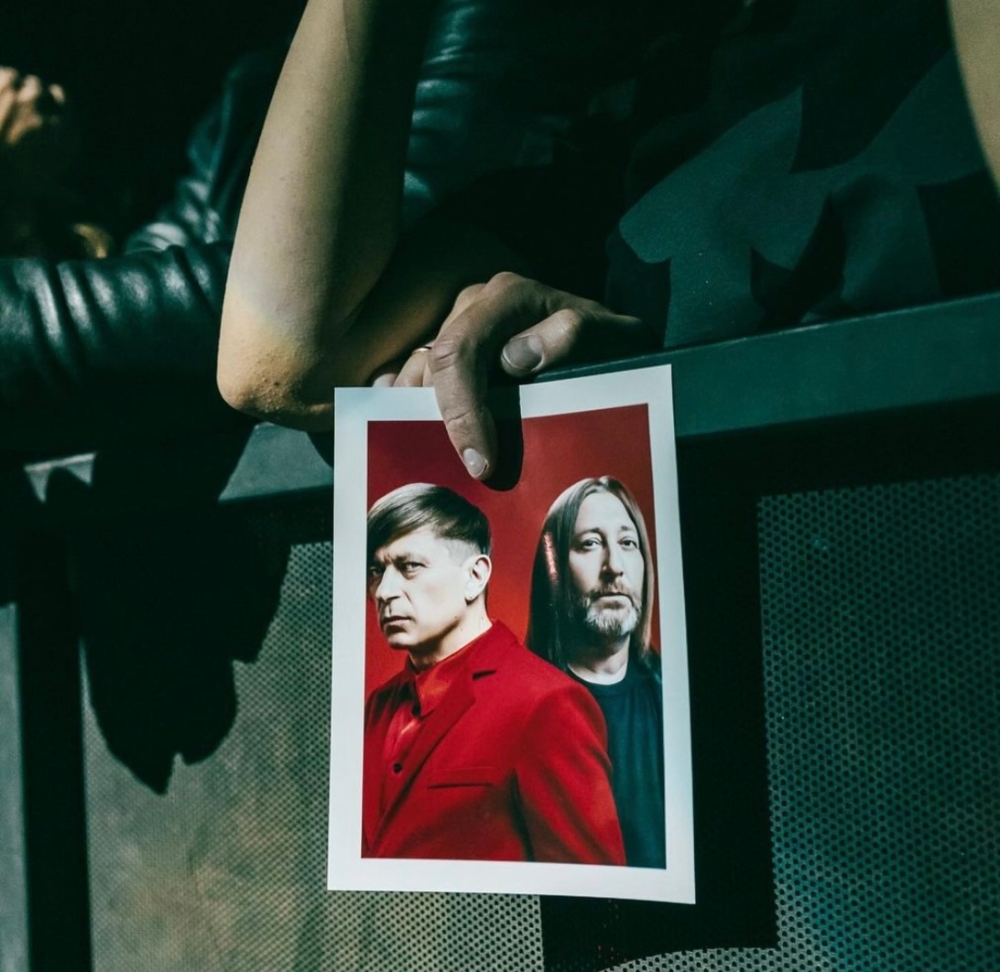 An audience member holds up a picture of the group Bi-2 at a performance venue. — Picture via Instagram/b2band