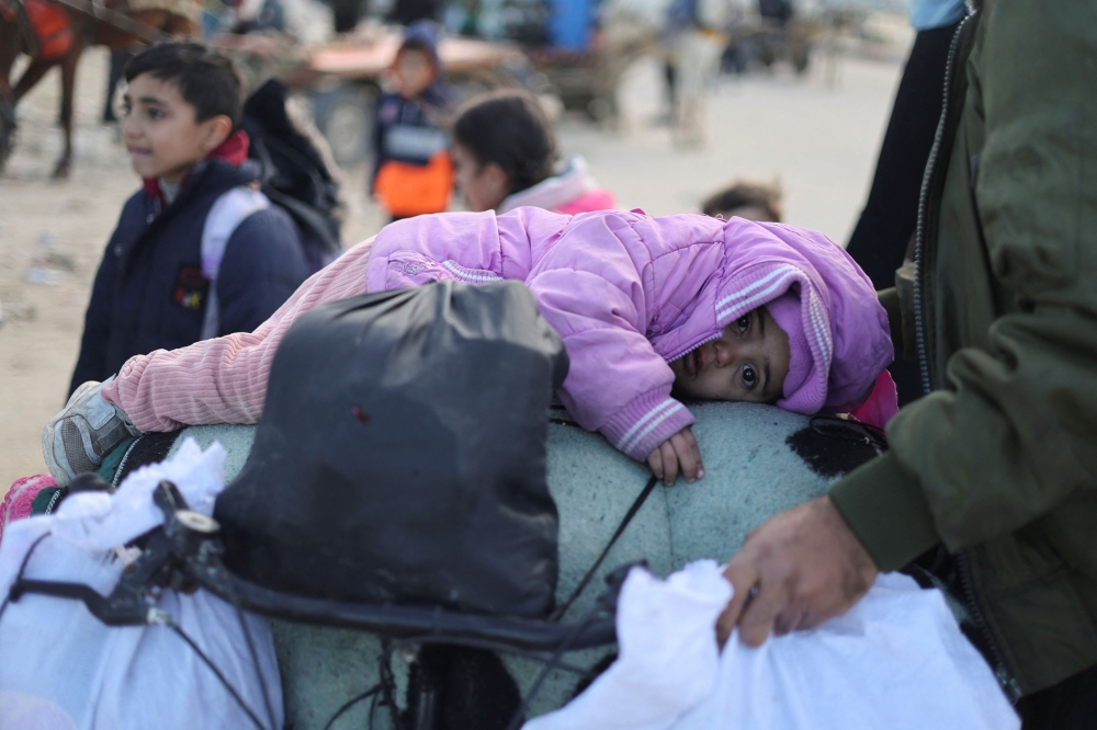 A child lies on a bicycle packed with belongings, as Palestinians flee Khan Younis towards Rafah, during the Israeli ground operation against Palestinian Islamist group Hamas, in the southern Gaza Strip, January 30, 2024. — Reuters pic
