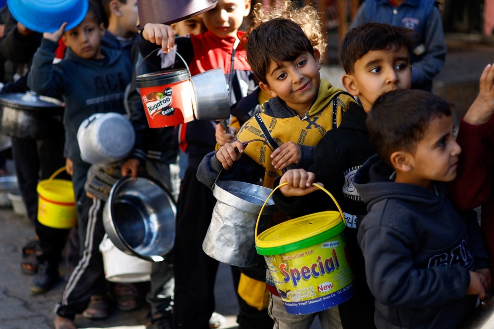 Palestinian children queuing for food at a charity kitchen in Rafah. — Reuters pic